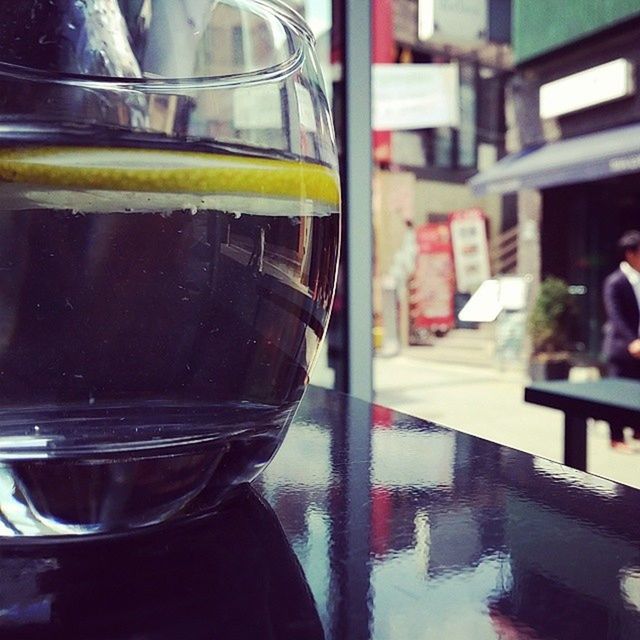 glass - material, indoors, transparent, reflection, window, focus on foreground, glass, incidental people, close-up, refreshment, built structure, architecture, day, street, drink, car, food and drink, yellow