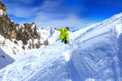 Full length of man snowboarding on snowcapped mountain against sky