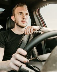 Portrait of young man sitting in car