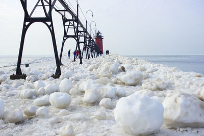 People walking on beach against sky during winter