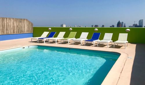 Swimming pool by sea against clear blue sky