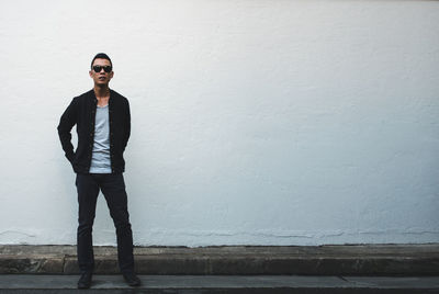 Front view of man standing against white wall