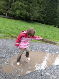 Full length of boy playing in puddle on field