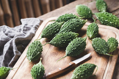 High angle view of bitter gourds with cutting board on wooden table