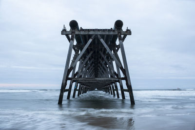 Abandoned industrial pier over sea against sky