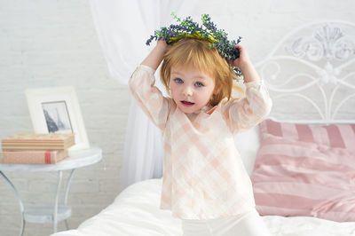 Portrait of cute girl sitting on bed at home