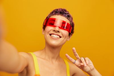 Portrait of young woman against yellow background