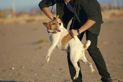 Low section of man holding dog standing on land