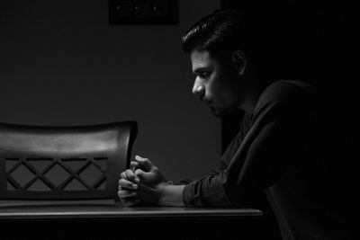 Side view of mature man sitting against gray background