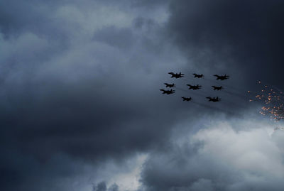 Low angle view of bird flying against cloudy sky