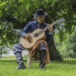 Full length of mature man playing guitar in public park