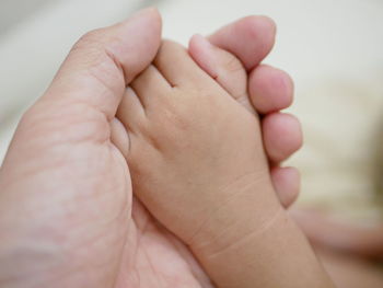 Cropped image of man holding baby hand