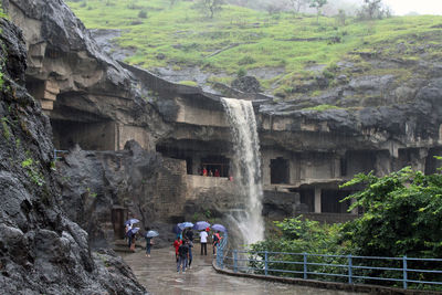 People walking on rocks against mountain