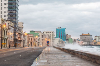 Road amidst buildings in city against sky