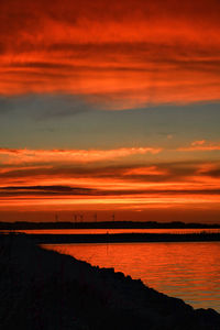 Scenic view of sea against dramatic sky during sunset