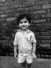 Portrait of smiling girl standing against brick wall