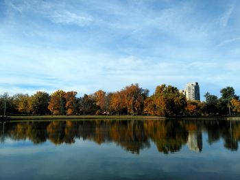 Scenic view of lake in front of trees against blue sky