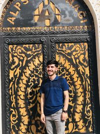 Portrait of young man standing against wall