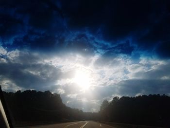 Road by trees against sky