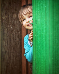 Portrait of cute boy looking out from a door