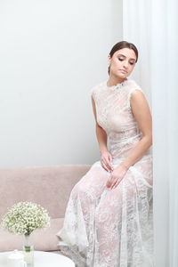 Portrait of young woman sitting against white background