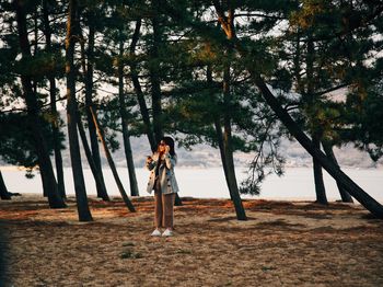 Portrait of young woman standing against trees