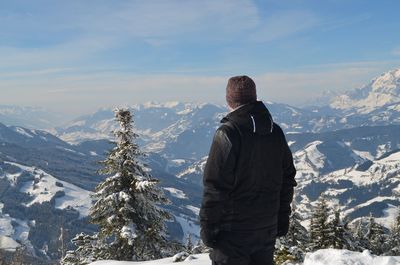Rear view of man looking at snowcapped mountains