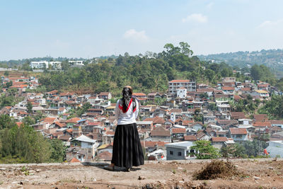 Woman standing by buildings against sky in city