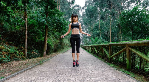 Full length of woman standing on bridge in forest