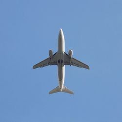 Low angle view of airplane flying against blue sky