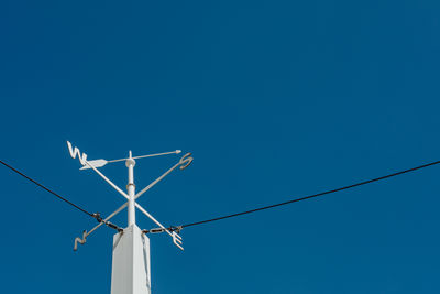 Low angle view of weather vane against clear blue sky