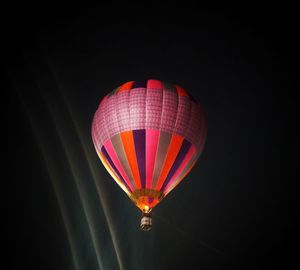 Low angle view of hot air balloon flying against black background