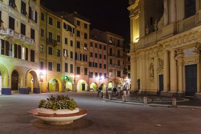 Illuminated street amidst buildings in city at night