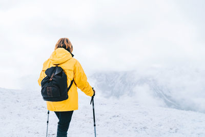 Back view of anonymous hiker with trekking poles walking on snowy ground in pyrenees mountains in andorra