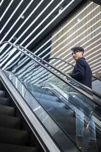 Handsome man with paper cup on escalator