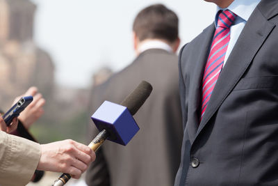 Cropped image of journalists with microphones taking interview of male politician