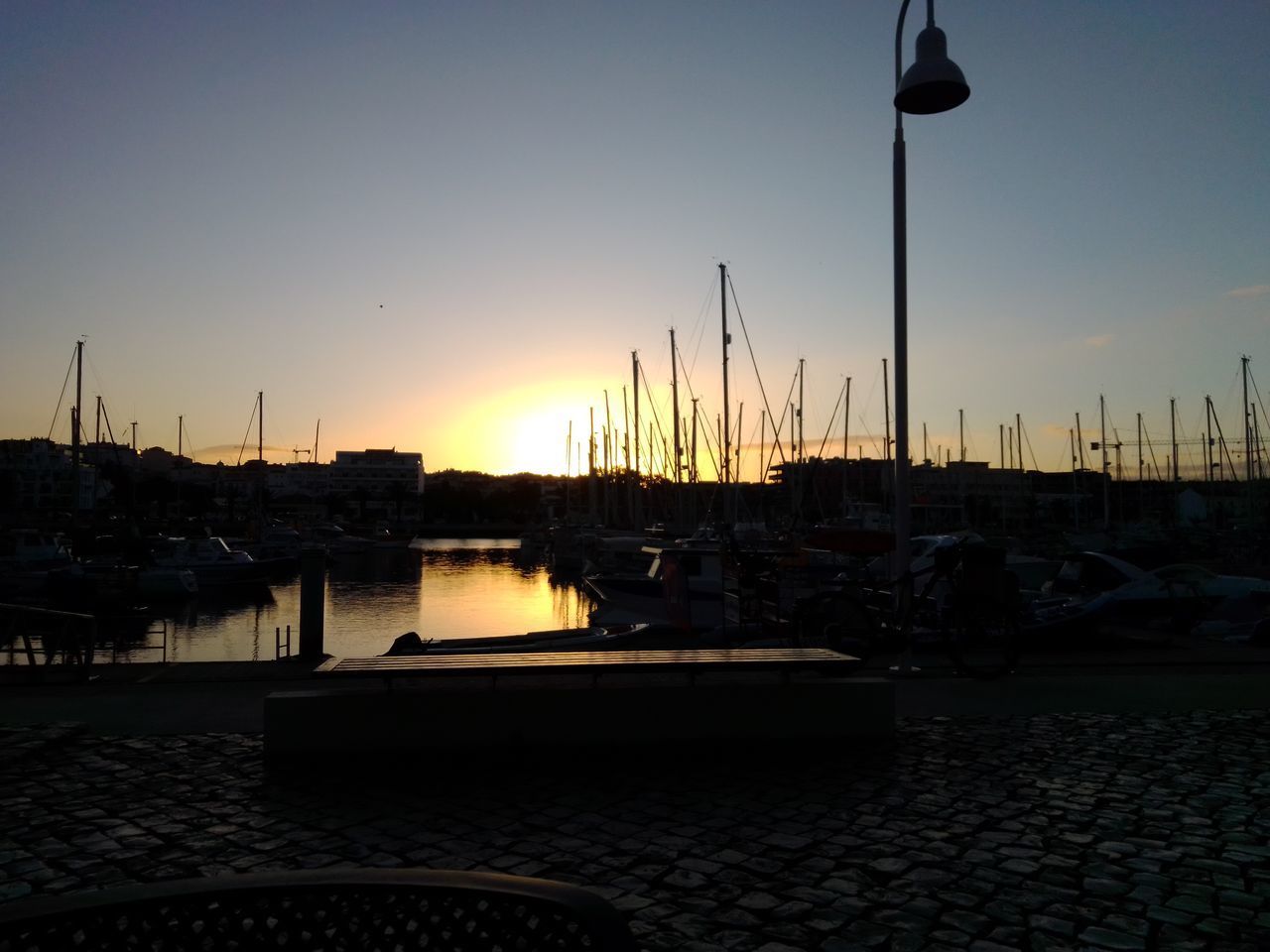 SAILBOATS MOORED IN HARBOR AT SUNSET