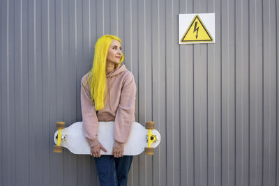 Woman holding yellow while standing against wall