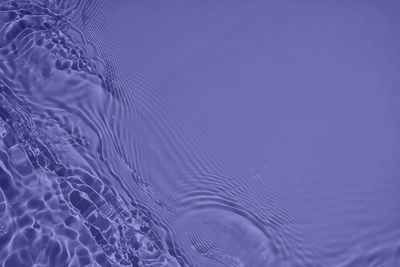 Transparent purple colored clear calm water surface texture