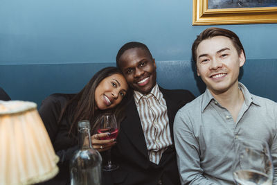 Portrait of smiling men with female friend holding wineglass in bar