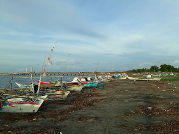 Boats moored on beach against sky