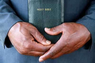 Midsection of man holding bible