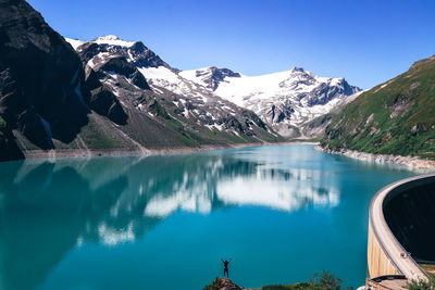 Scenic view of lake by snowcapped mountains against sky