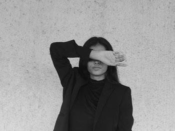 Portrait of a young woman wearing a blazer standing against wall