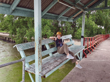 an asian woman sitting on the bench at colorful historic local pier in thailand