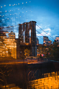 Bridge over illuminated buildings against sky at night