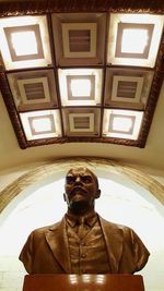 Low angle portrait of man standing against window