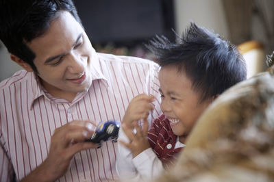 Father and son sitting on sofa at home