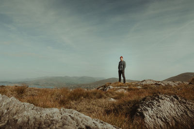 Rear view of man standing on mountain against sky