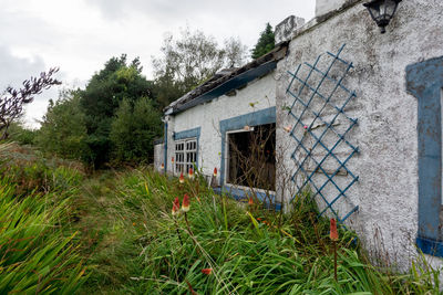 Exterior of abandoned house on field against sky